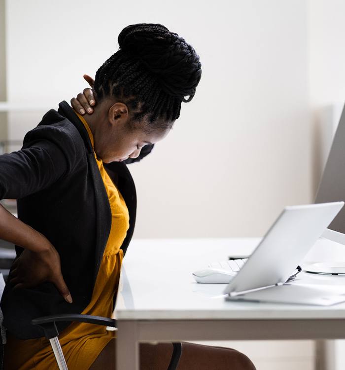 woman holding neck and back while sitting at desk