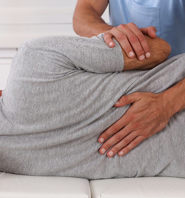 doctor pressing on patient’s back on massage table 