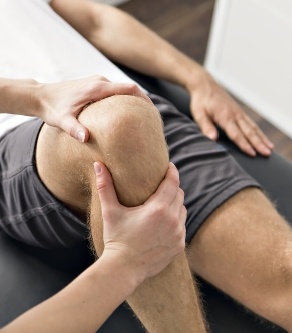 Doctor performing non surgical orthopedic treatment on patient's knee