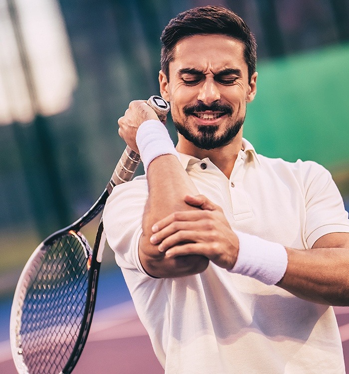 Tennis playing pain holding elbow before osteopathic manipulative treatment