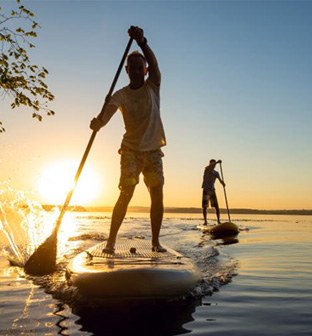 Two people paddleboarding at sunset