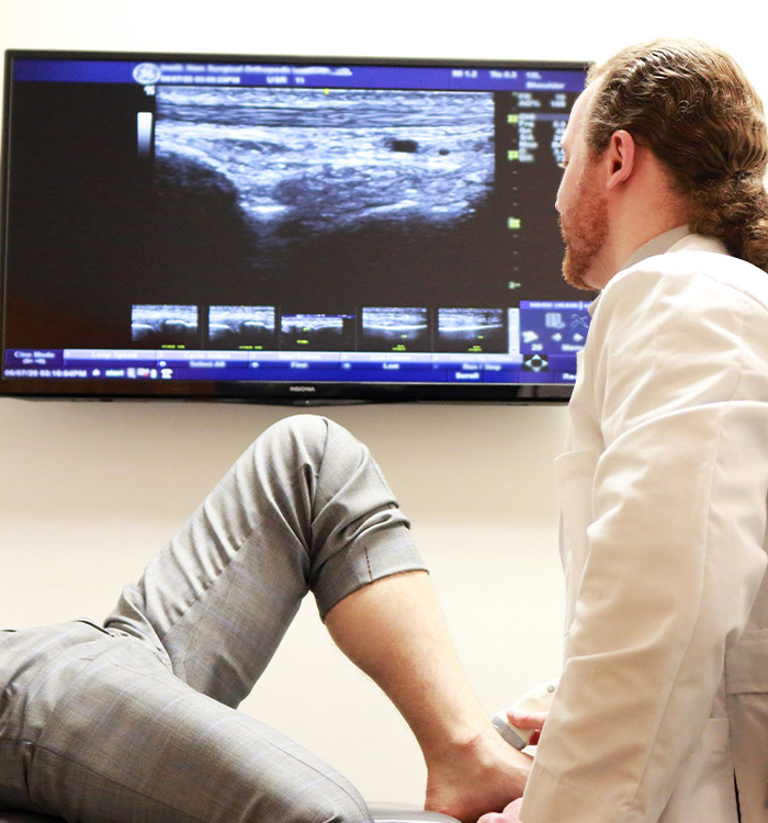 Physician performing musculoskeletal ultrasound during non-surgical orthopedics visit