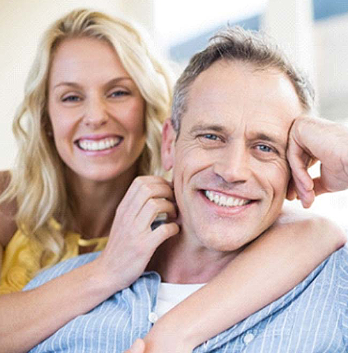 mature man smiling with wife on couch