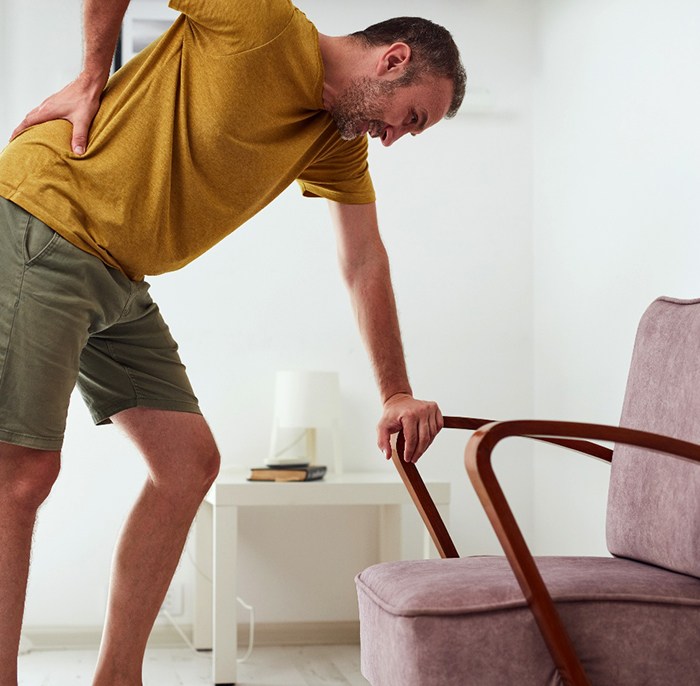 Man leaning on his chair, dealing with pain