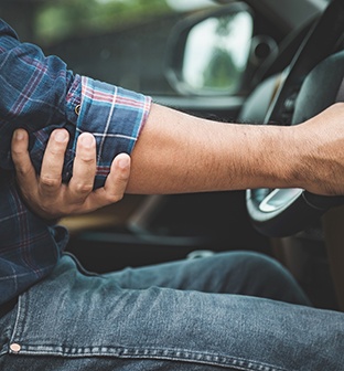 Man struggling with elbow pain while driving