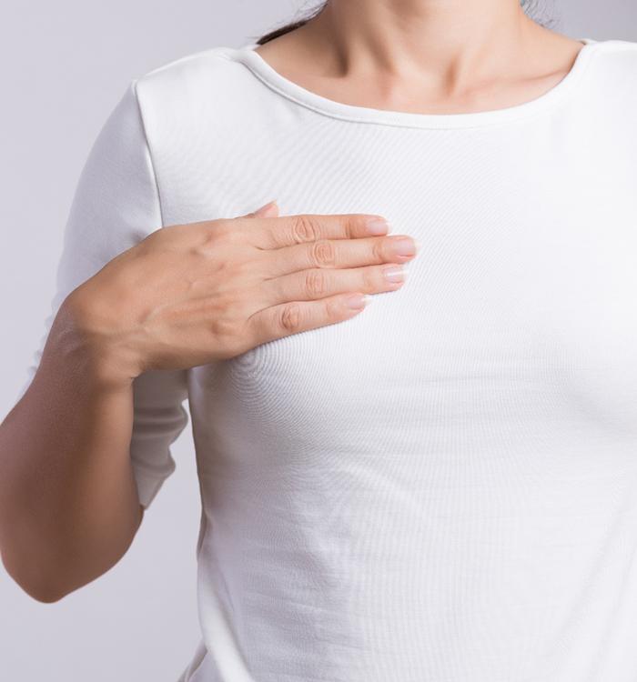 woman in white shirt touch the top of her breast 