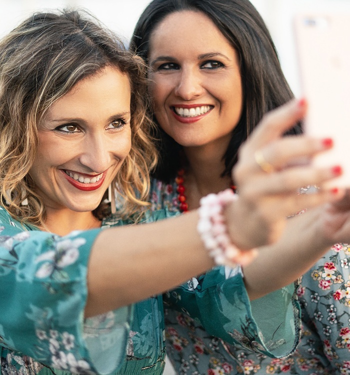 two 40-something women smiling taking a selfie 