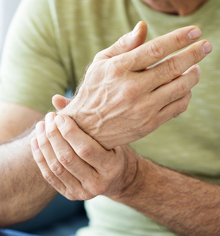 Man in pain holding wrist before chronic pain counseling