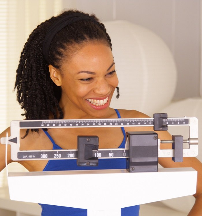 Happy woman looking at scale after weight loss counseling