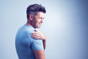 Grimacing man experiencing shoulder pain